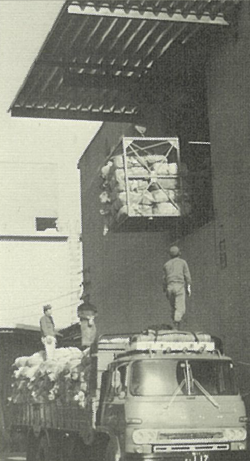 荷物を載せたトラックと、建物の上階へ荷物を吊り上げている写真